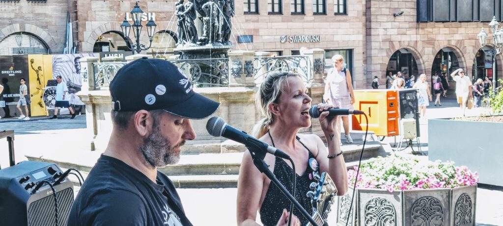 Ariwa Demo in Nürnberg, Sabine und Neil beim singen auf der Demo von der Seite fotografiert.